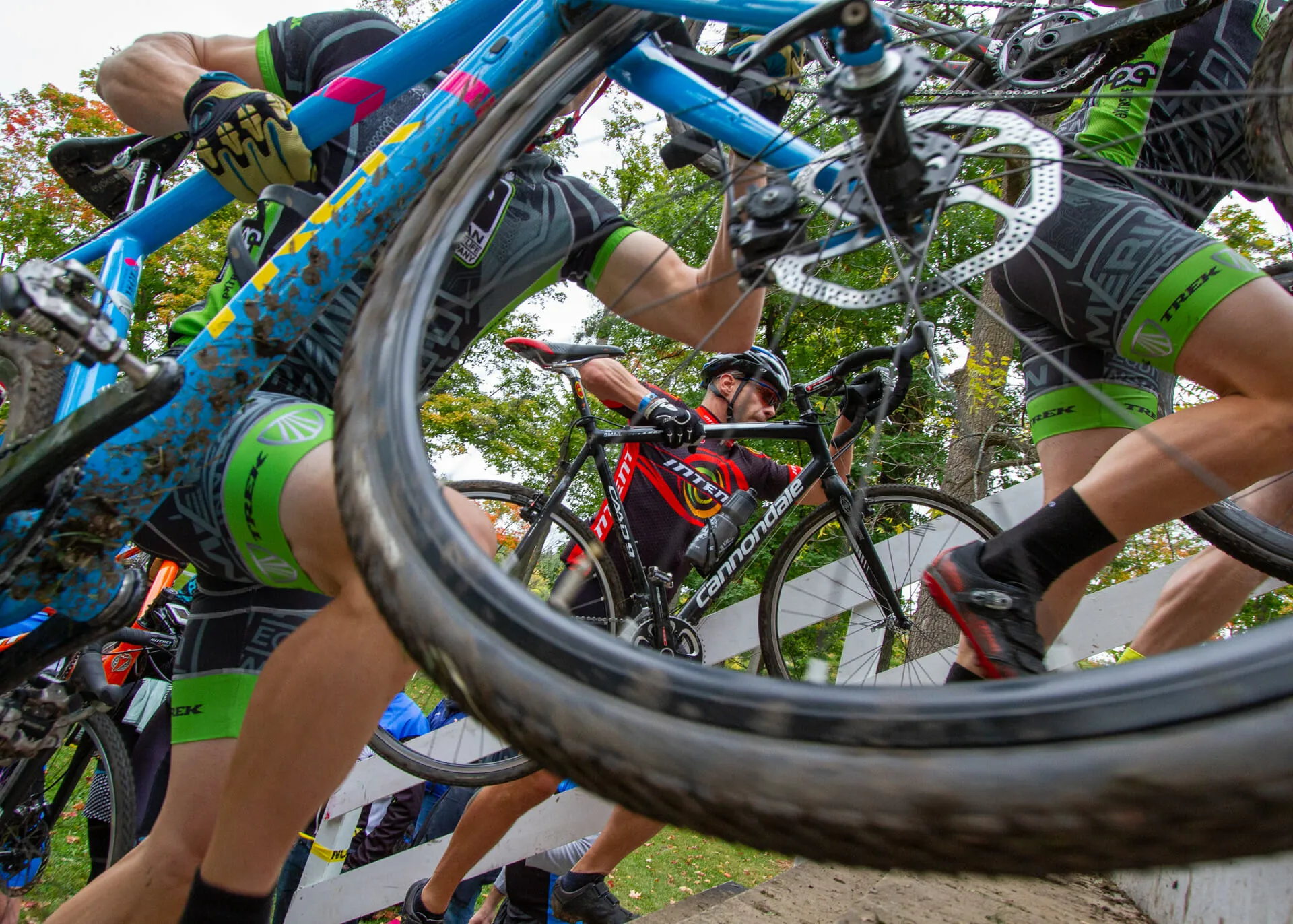 Cyclocross racers shouldering their bikes over the barriers