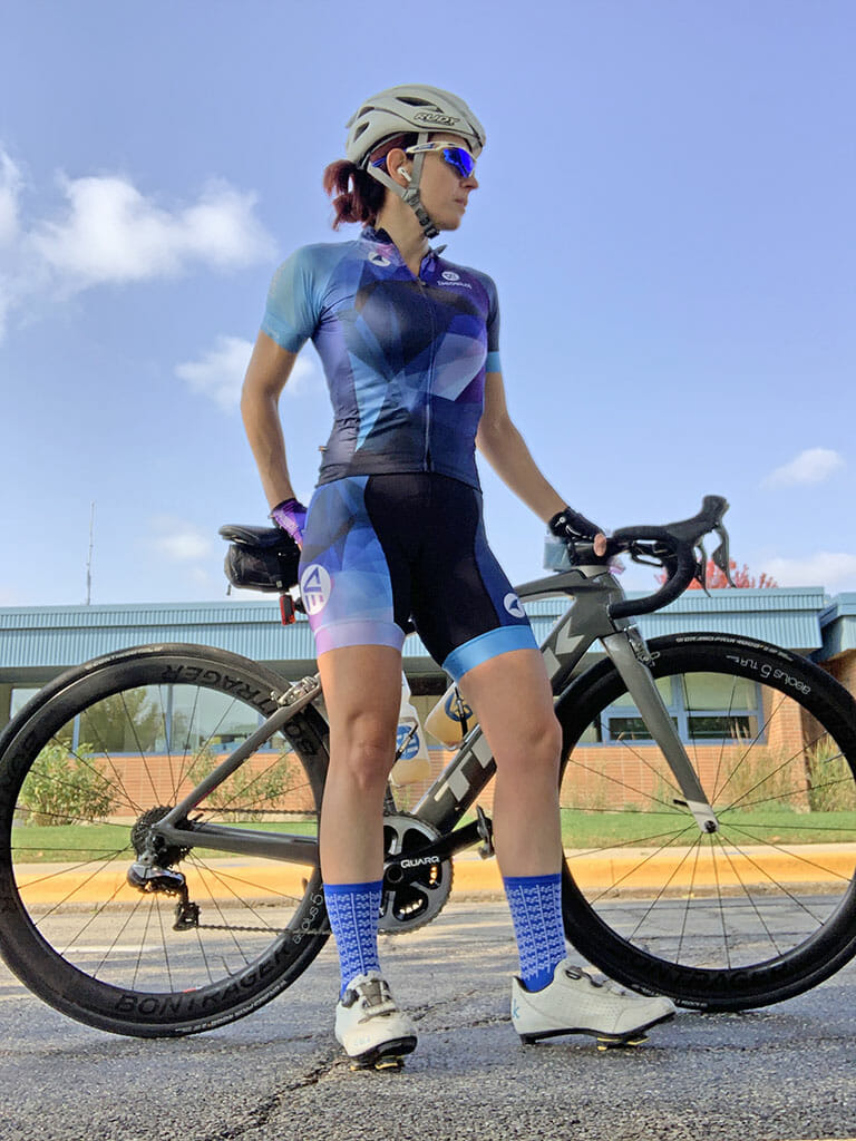 Theia Friestedt wearing the [360 VELO] kit standing with Trek Madone 9 on a sunny day with blue sky