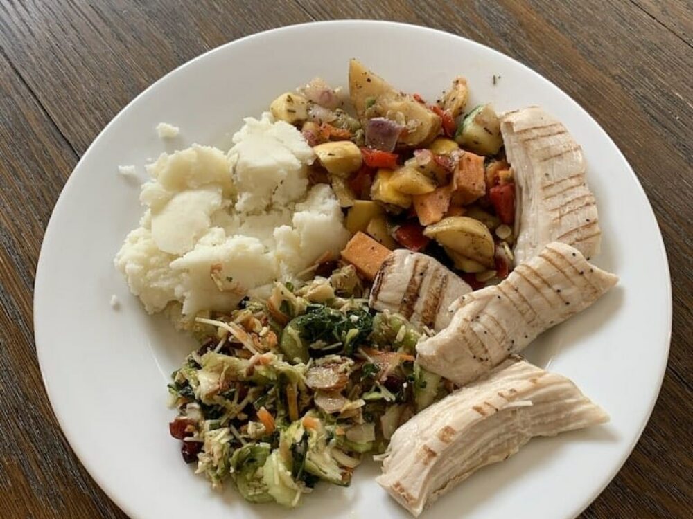 Healthy food plate with mashed potatoes, grilled mixed root vegetables, shaved sprouts, and grilled chicken